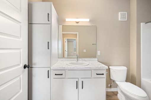A white bathroom with a sink, toilet, and medicine cabinet.
