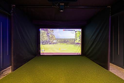 A screen in a dark room shows a golf course.