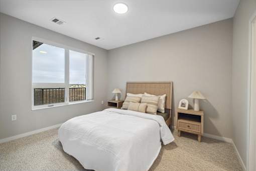 a white bedroom with a large window and a bed