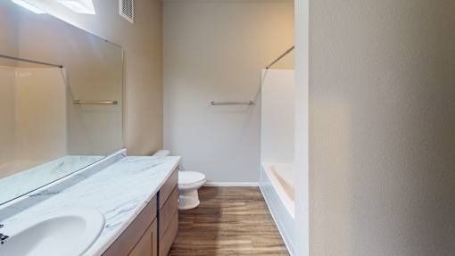 A bathroom with a toilet, sink, and mirror.