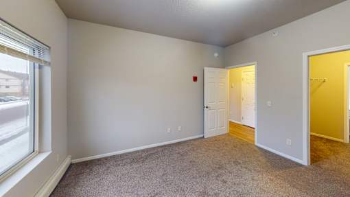 A room with a carpeted floor and two doors, one of which is open.