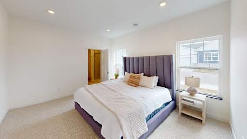 A bedroom with a bed, nightstand, and window.