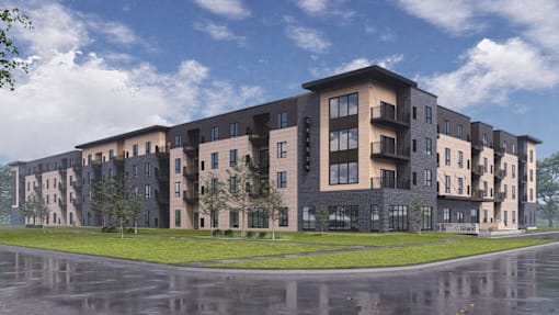 A modern apartment building with a wet street in front.