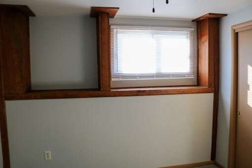 A room with a window and a white wall.