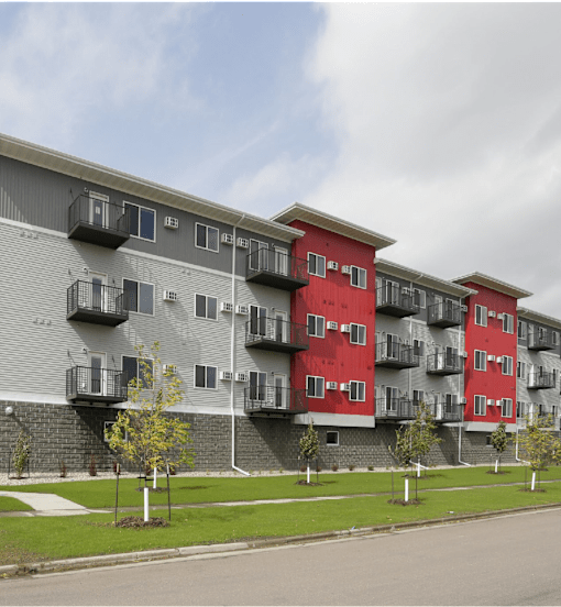 Apartment building with red and grey exterior and balconies.