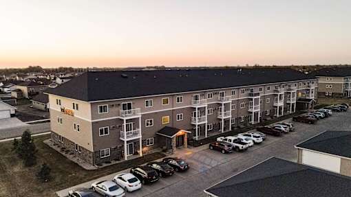A parking lot in front of a multi-story apartment building.
