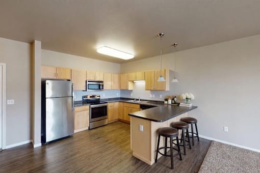 A kitchen with a refrigerator, microwave, oven, and bar stools.