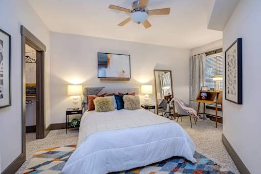A bedroom with a large bed and a ceiling fan.