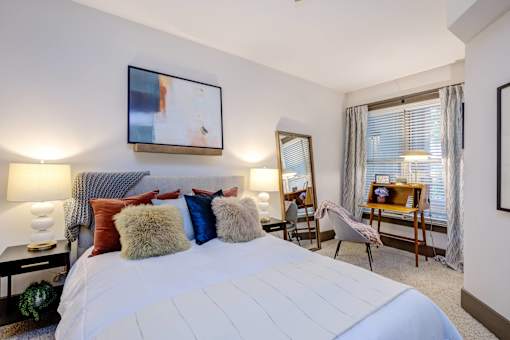 A bedroom with a large bed and a painting on the wall.