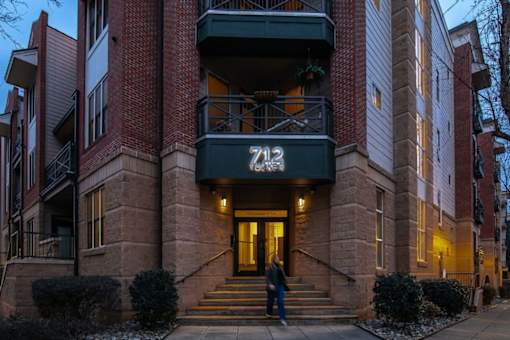 Two people are standing at the entrance of a building with the number 742 on it.