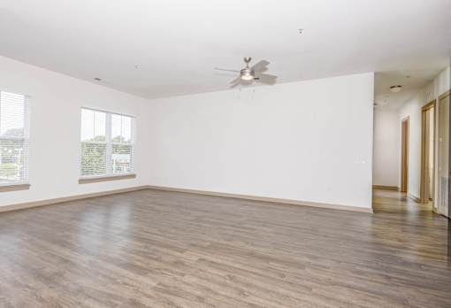 A room with a ceiling fan and wooden flooring.