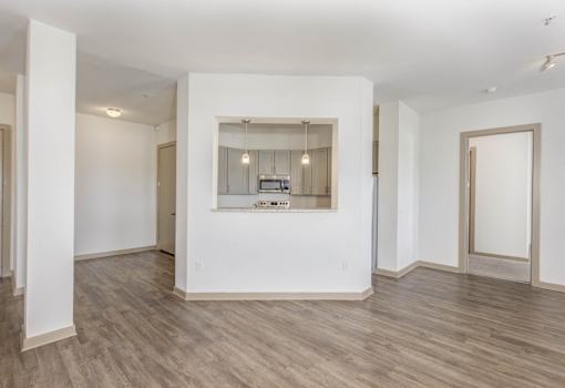 A spacious room with a large window and wooden flooring.
