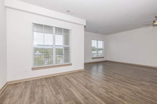 A room with wooden flooring and a window with blinds.