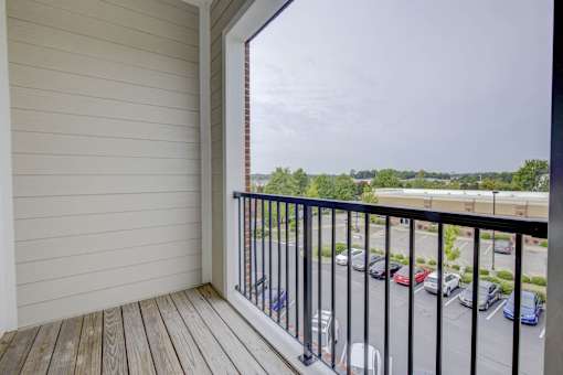 A balcony with a black railing overlooks a parking lot.
