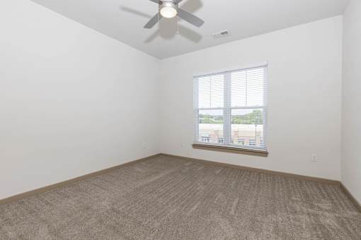 A room with a ceiling fan and a window with blinds.