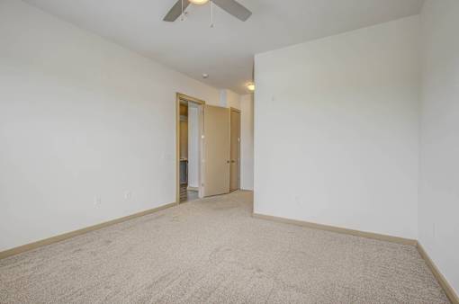 A room with a carpeted floor and a ceiling fan.