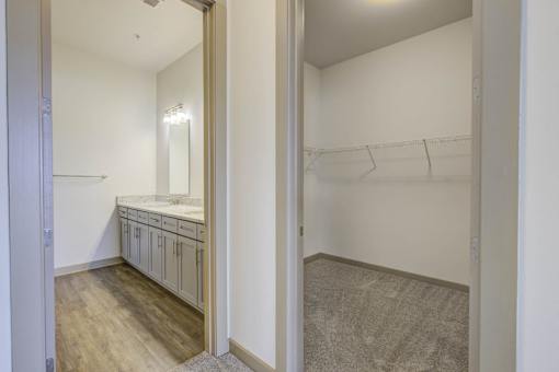 A walk in closet with a mirror and shelves.