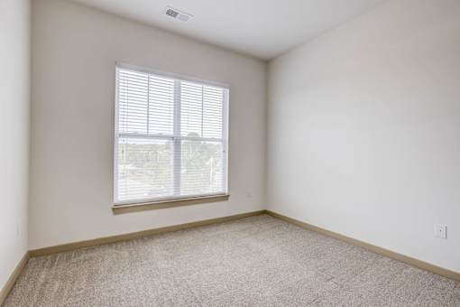 A room with a window and carpeted floor.
