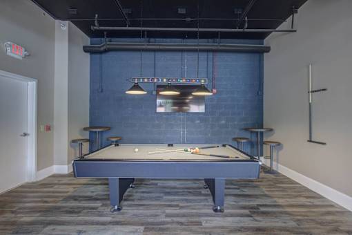 A pool table is in the middle of a room with a blue wall.