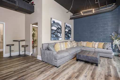 A grey couch with yellow pillows sits in a room with wooden floors.