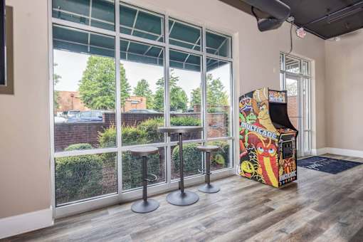 A room with a pinball machine and two stools.