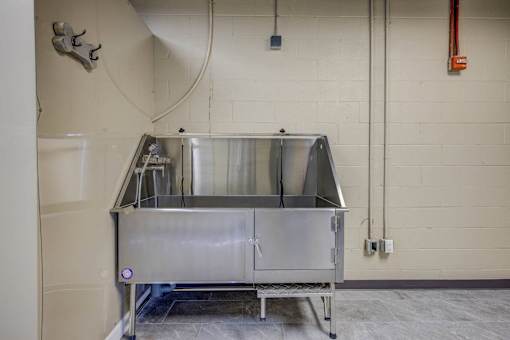 A large metal container sits on a metal frame in a room with white walls.