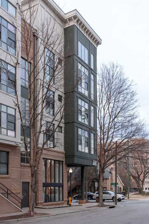 A building with a dark grey facade stands on a street corner.