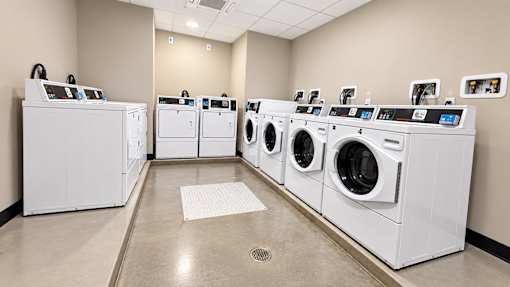 A row of white front load washing machines in a laundromat.