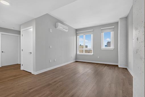 A room with a wooden floor and a window overlooking a cityscape.
