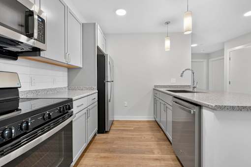 A modern kitchen with stainless steel appliances and wooden floors.