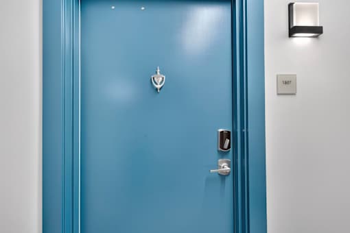 A blue door with a silver handle and a silver lock.