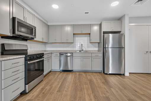 A modern kitchen with stainless steel appliances and wooden flooring.