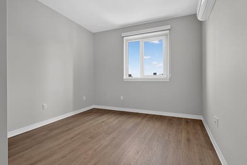 A room with a window and wooden flooring.