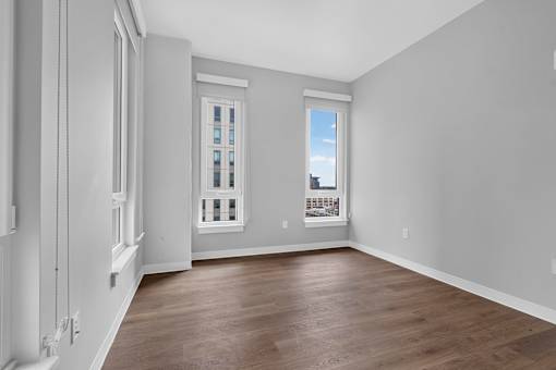 A room with a window and a wooden floor.