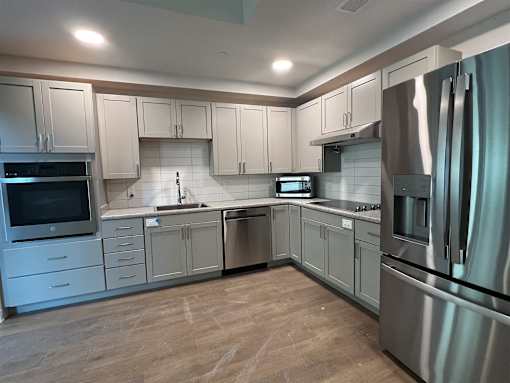 A modern kitchen with stainless steel appliances and wooden floors.