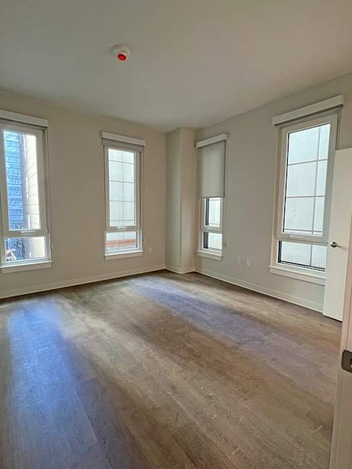A room with wooden floors and three windows.