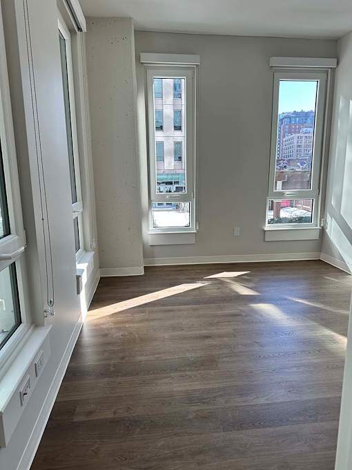 A room with wooden floors and two windows.