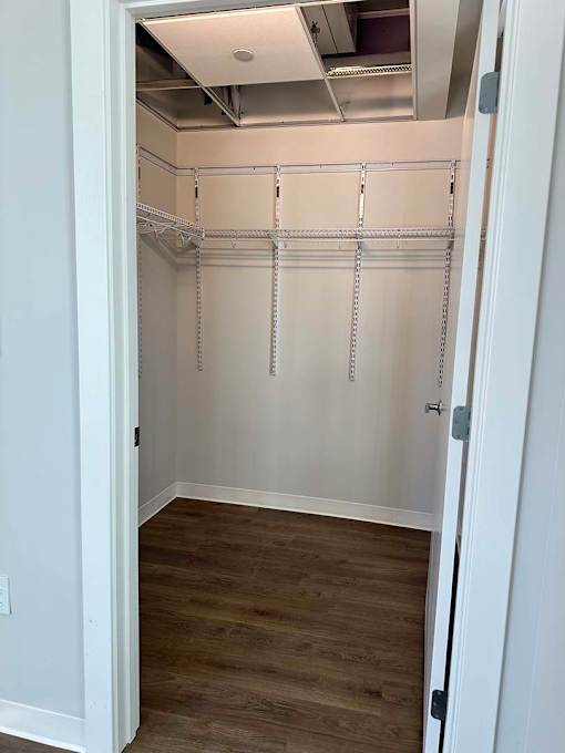 A white closet with wood flooring and a white door.