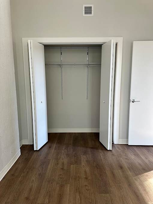 A white closet with a door open and a shelf above.