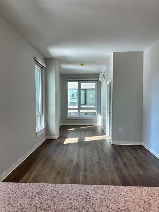 A long, empty hallway with a window and a door.