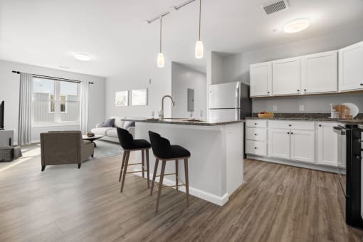 a kitchen with white cabinets and an island with two chairs