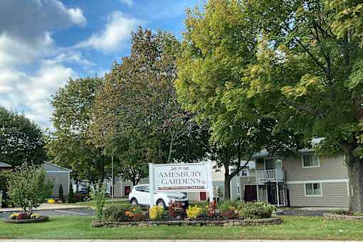 A sign for Amesbury Gardens is in front of a building.