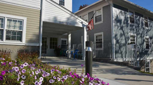A building with a sign that says "Intrepid House" is surrounded by flowers.