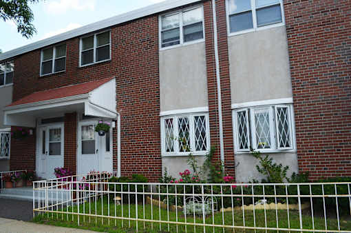 A red brick house with a white fence in front.