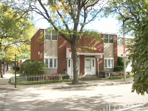 A red brick house with a white fence in front.