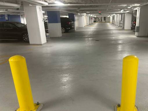 A parking garage with a yellow pole in the foreground.
