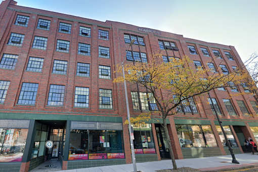 A red brick building with a tree in front of it.