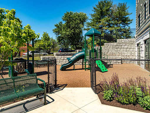A playground with a green slide and a green bench.