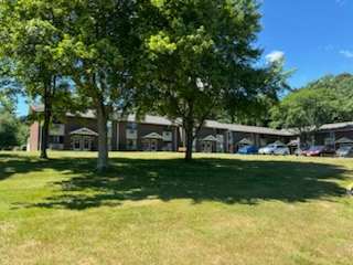 A grassy area with trees and a building in the background.