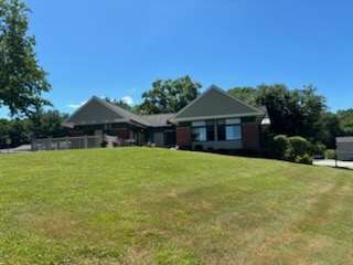 A house with a grey roof and a green lawn in front.